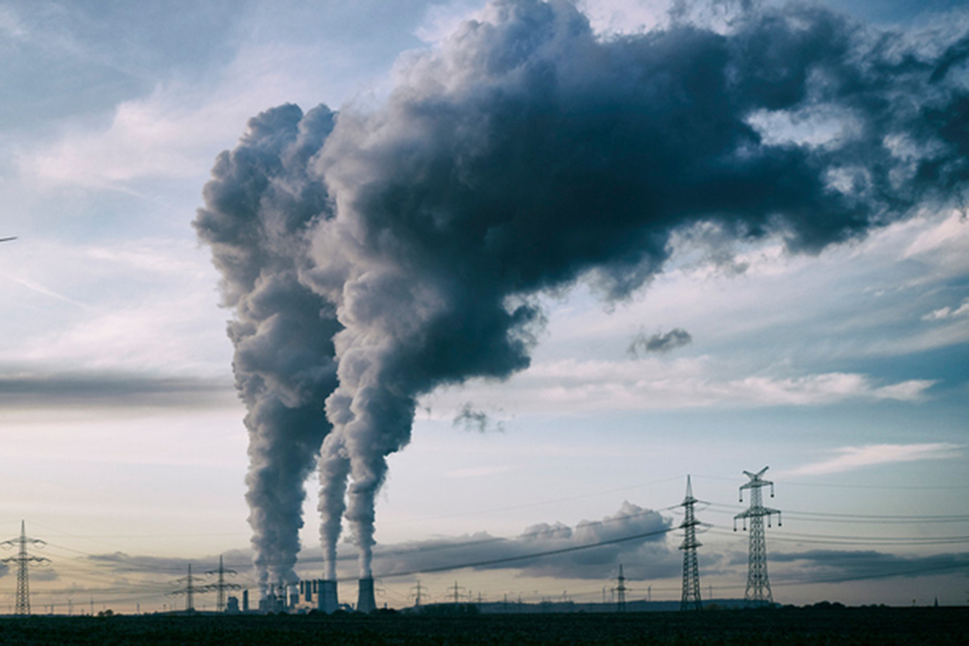 Smoke is shown billowing from stacks seen at a distance.