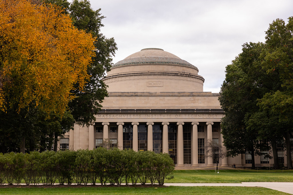 A photo of MIT's Killian Court with the Great Dome in the center of the image and trees surrounding