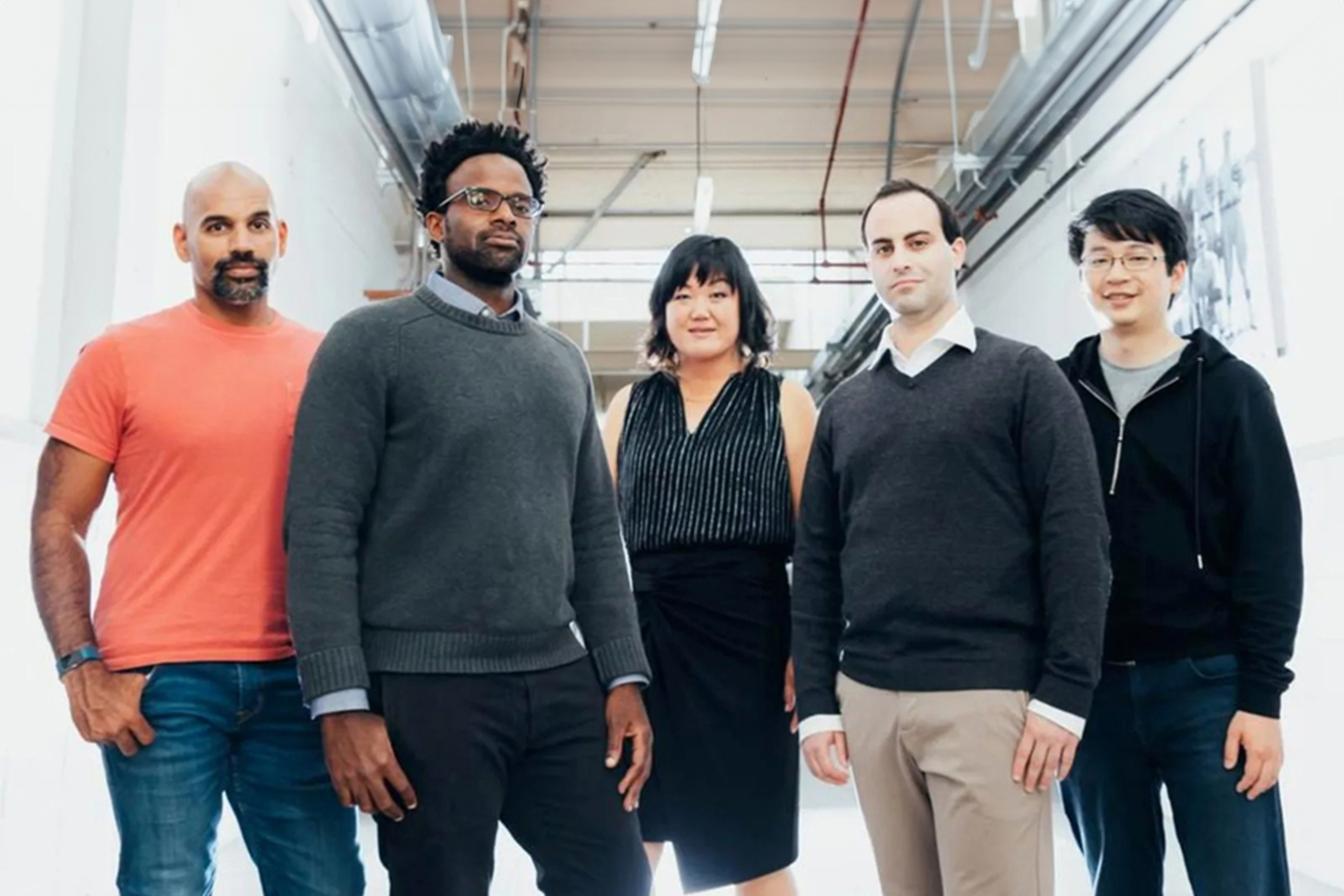 From left, Naveen Rao, Michael Carbin, Julie Shin Choi, Jonathan Frankle, and Hanlin Tang pose in a hallway.