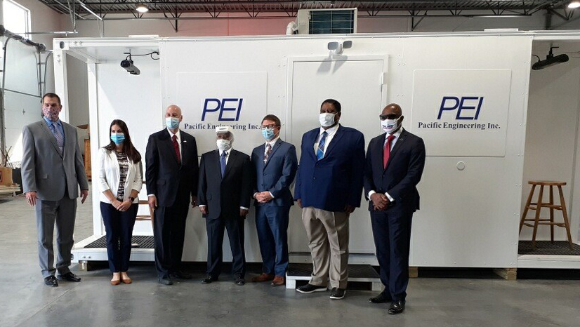 A group of people pose with a Covid testing mobile unit