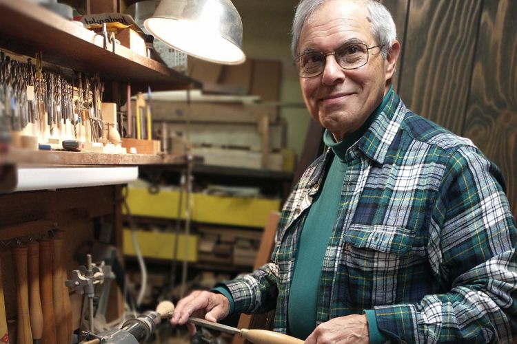 A photo of Mark Horowitz in his workshop turning the handle of a baton on the lathe