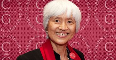 Headshot of Sze-Wen Kuo against a background showing the logo of the Cardinal & Gray Society.